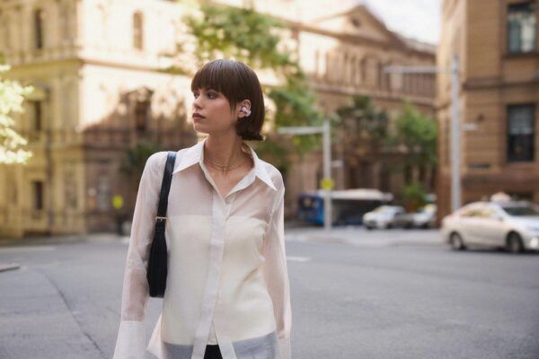 Mujer caminando por la ciudad con los auriculares Sony LinkBuds Clip de diseño abierto